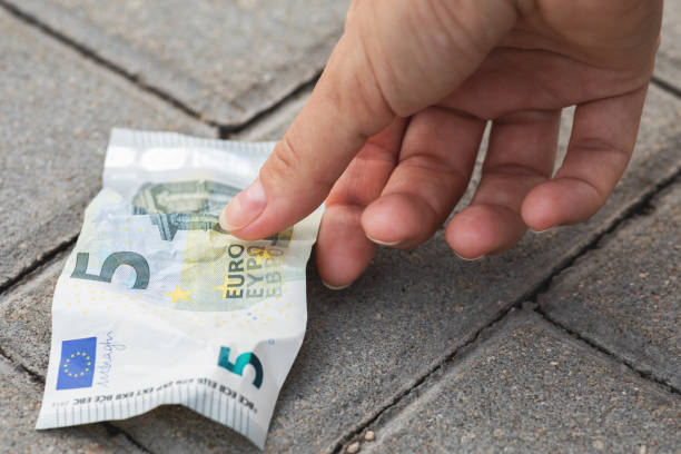 Lost and found money. Woman is picking five euro banknote from the ground.